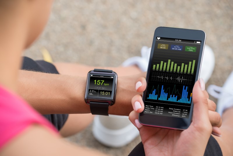 Frau benutzt Fitness Tracker mit passender Tracking-App am Smartphone